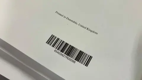 Sam Read/BBC A bar code on the back of a book, showing where it is printed. The book is on white paper and has "Printed in Dunstable, United Kingdom" written on the back.