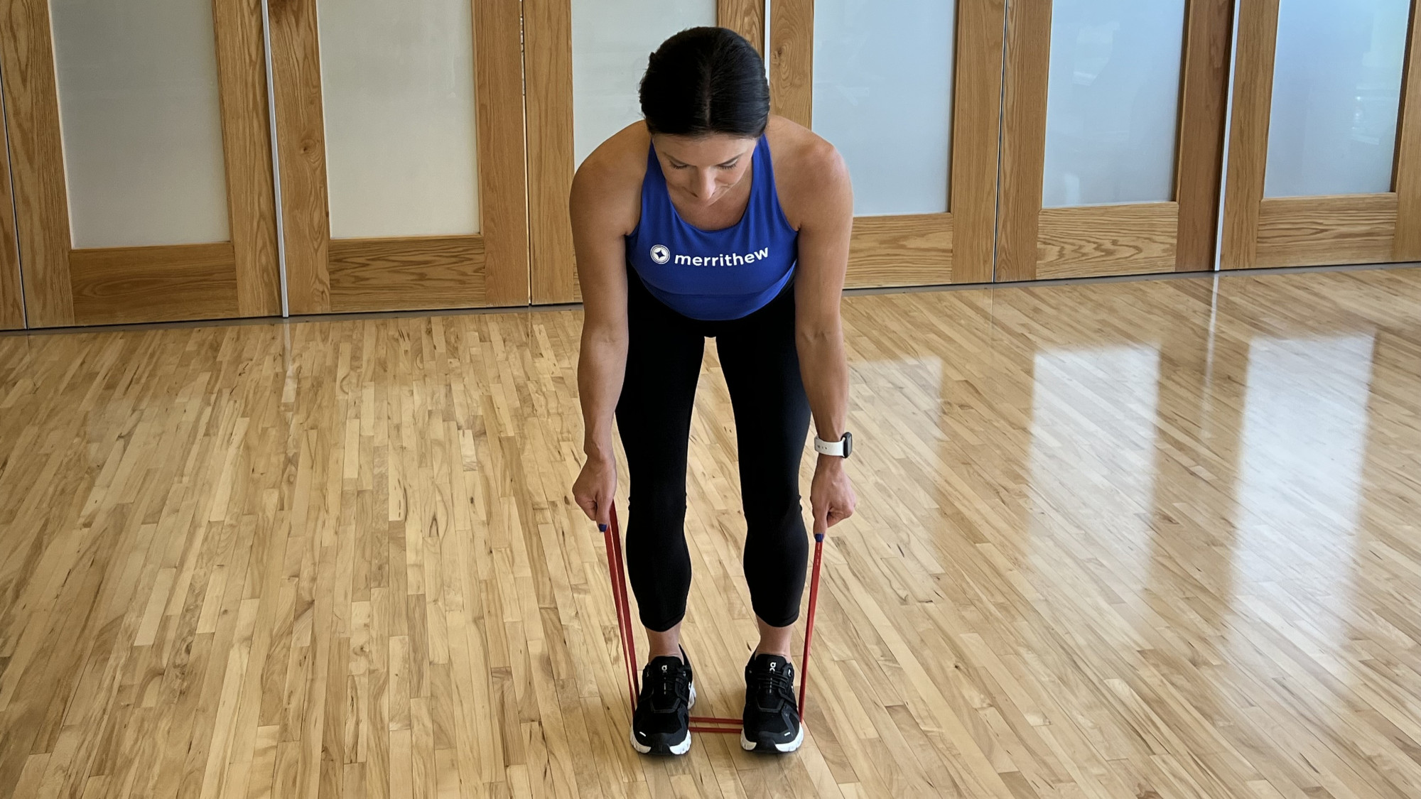 Woman demonstrates exercise using resistance band in fitness studio