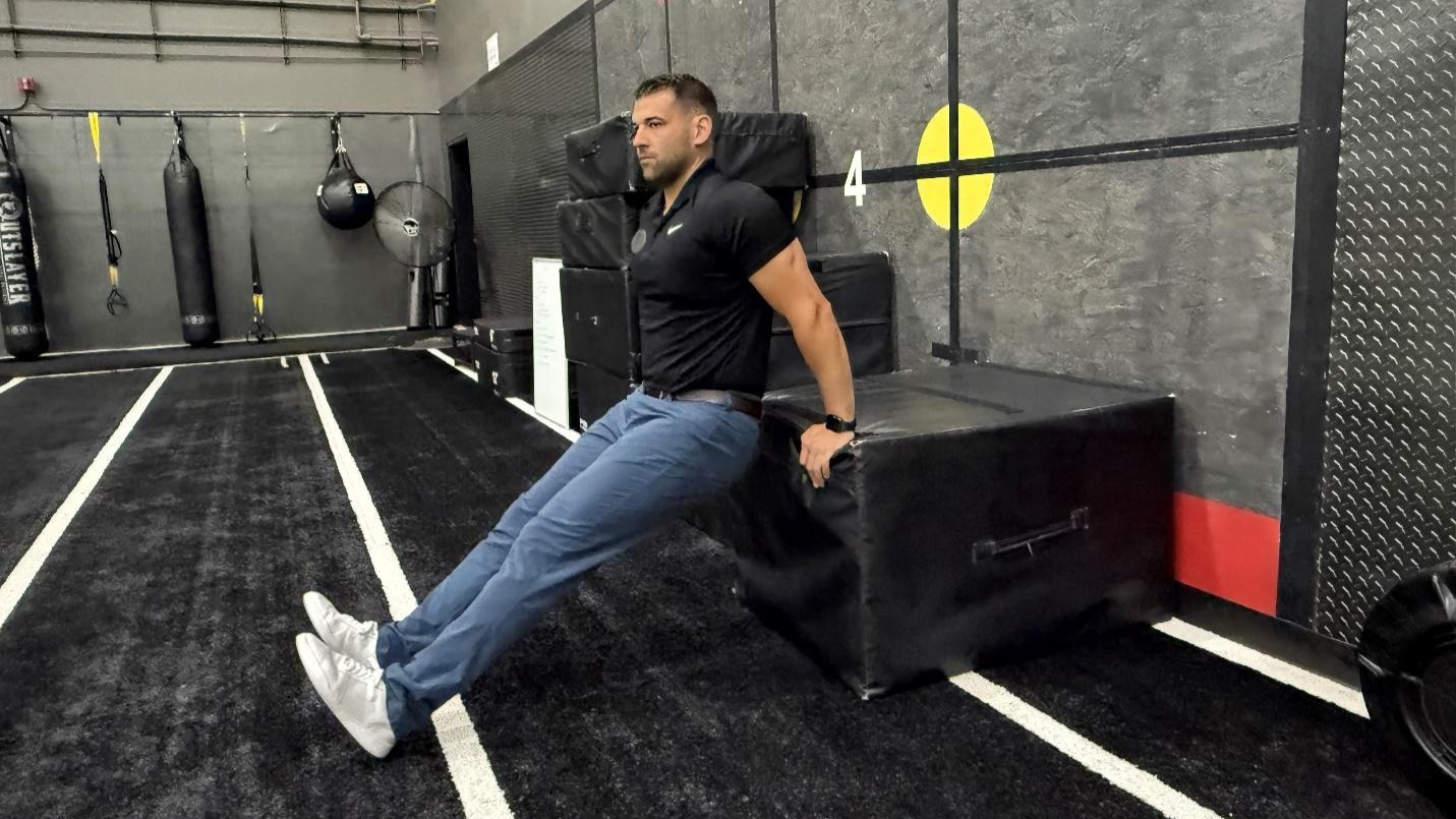 Man in start position for triceps dip in gym