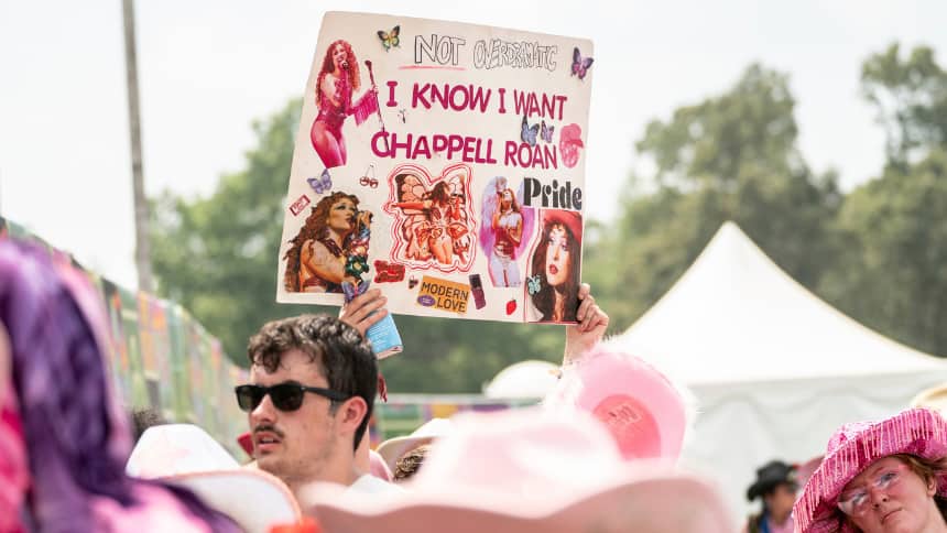 A Chappell Roan fan holds up a homemade sign with photos of the singer on it.