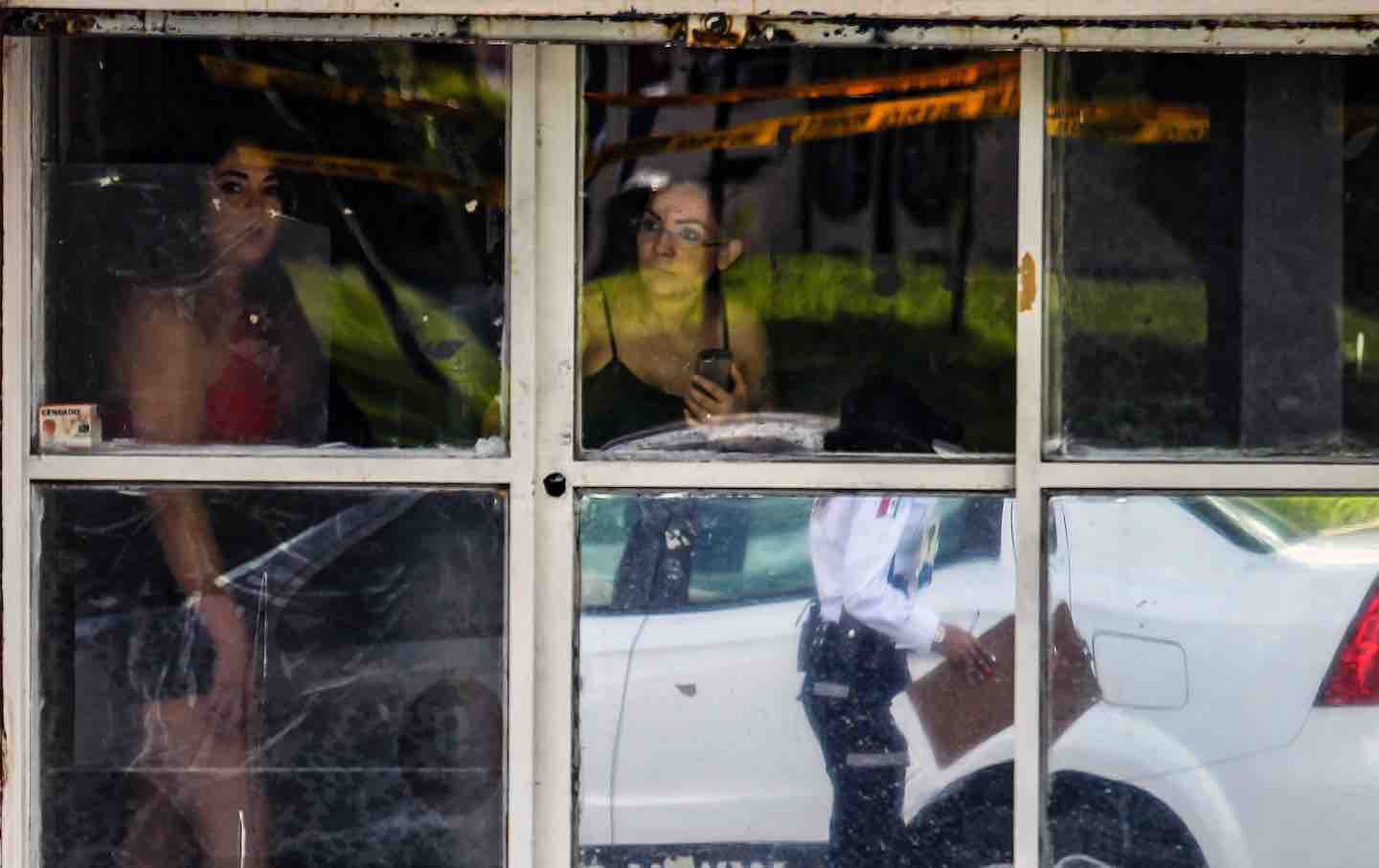 Locals stare at the crime scene from a window after a man was shot dead in Guadalajara, Jalisco State, Mexico, 2018.