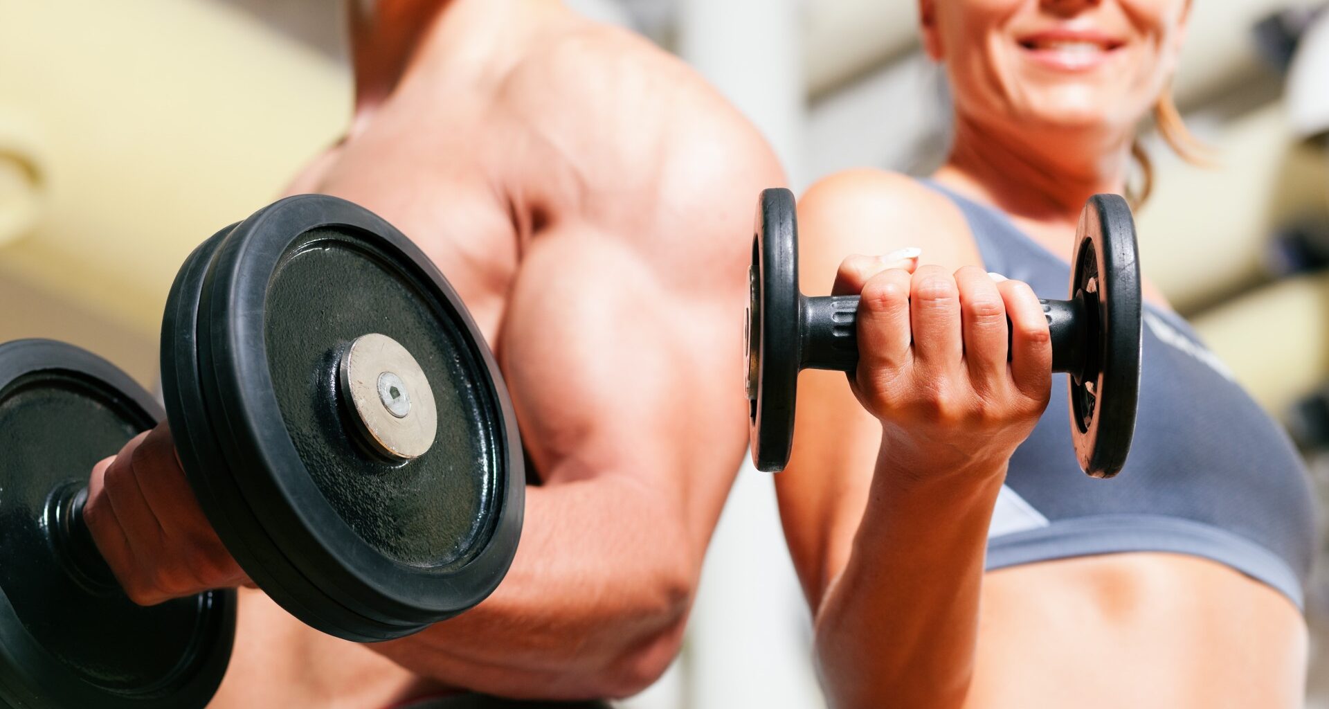 Man and woman holding a dumbbell in hand performing a bicep curl