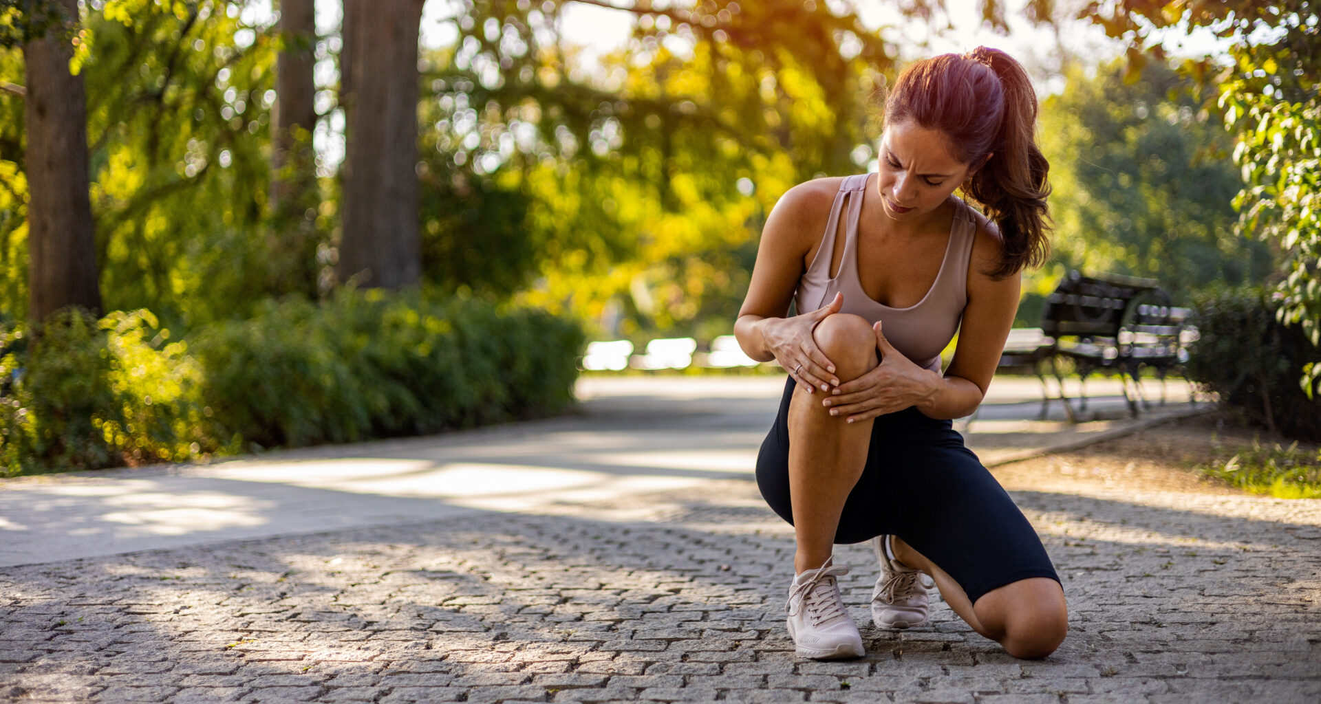 Injured female runner holding knee