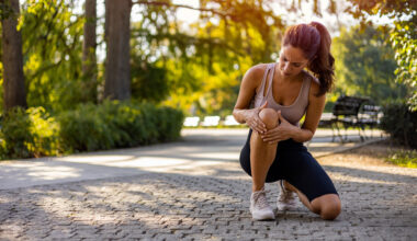 Injured female runner holding knee
