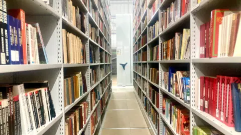 Mousumi Bakshi/BBC Image shows floor-to-ceiling shelves known as rolling stacks holding hundreds of books.