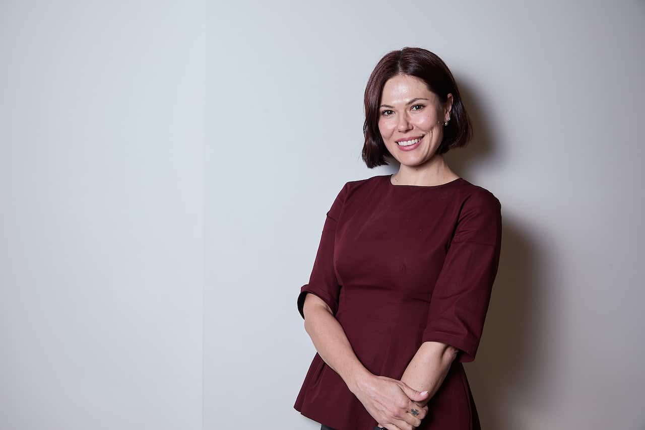 A woman smiles into the camera. 
