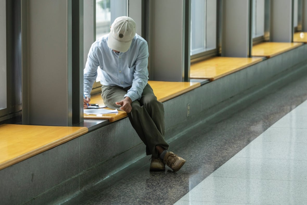  A man sits in the window of a conference hall to fill out an application.