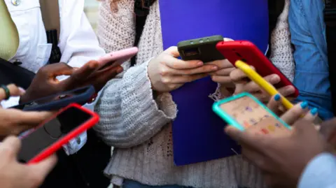 Getty Images A group of children in school holding phones.