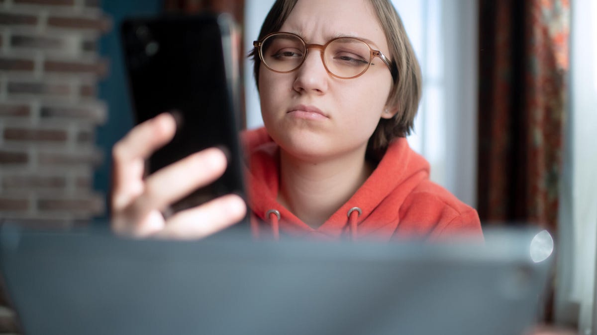 A person looks at their phone with a look of confusion.