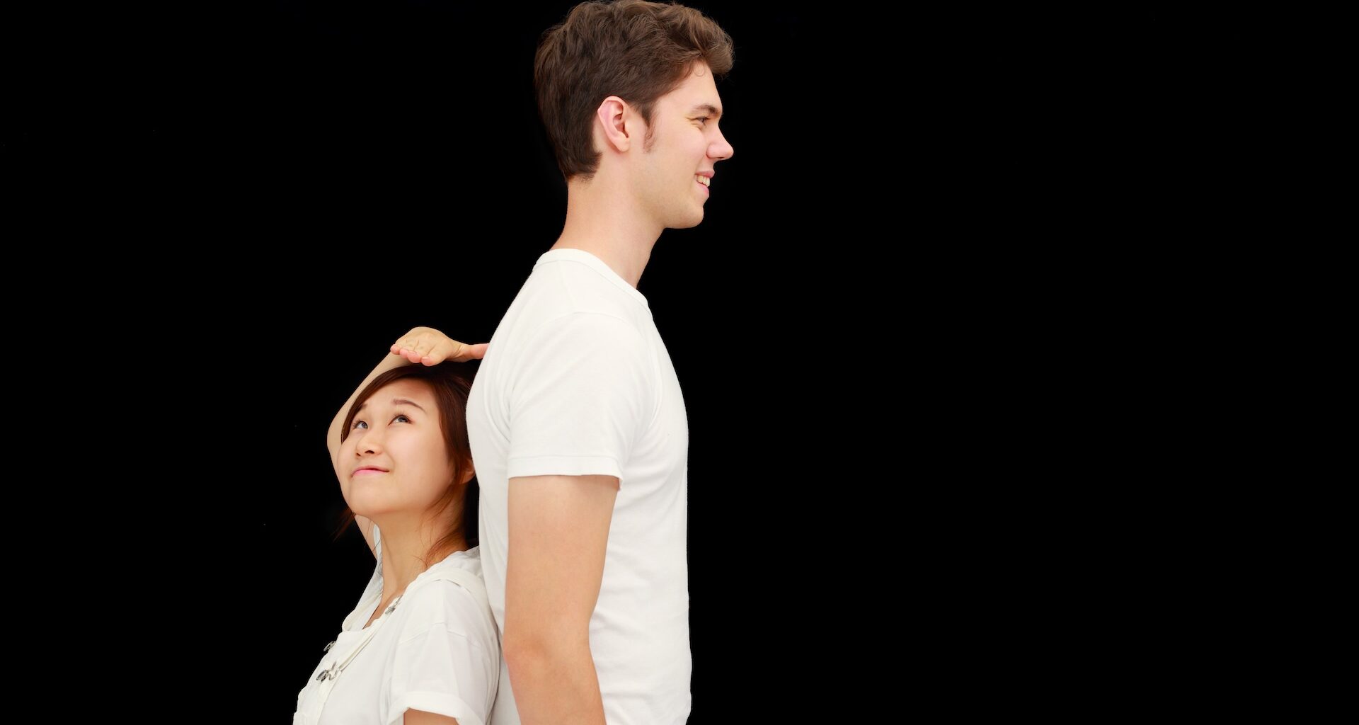 a short woman stands back-to-back with a much taller man