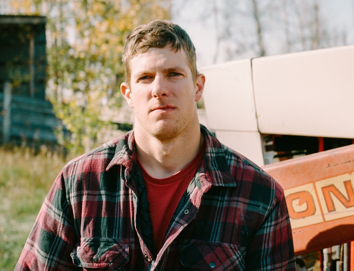 Kole Norman stands solemnly in front of a tractor.