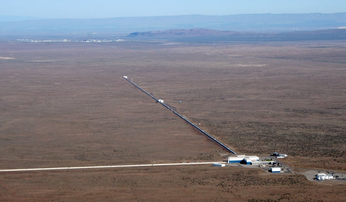 A building with two long metal arms stretch into an empty, dusty landscape. 