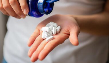 A person pouring white pills into their hand out of a blue pill bottle.