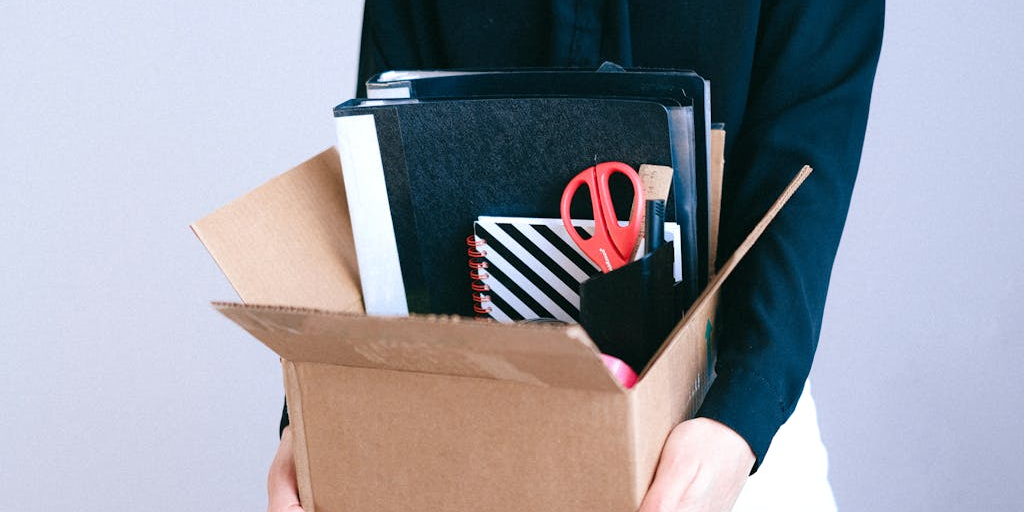 Person holding an open box full of office supplies