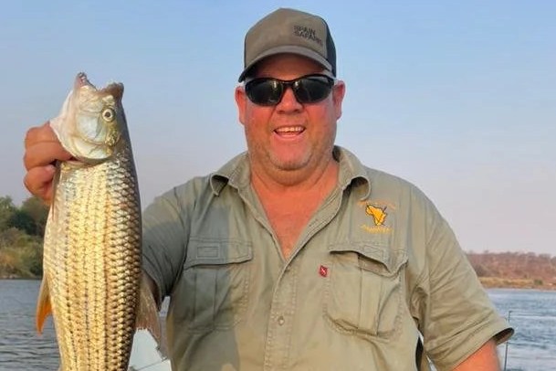 Man holding a large fish in a boat.