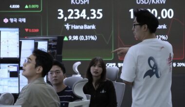 Currency traders work near a screen showing the Korea Composite Stock Price Index (KOSPI) and the foreign exchange rate between U.S. dollar and South Korean won, right, at the foreign exchange dealing room of the Hana Bank headquarters in Seoul, South Korea, Thursday, Aug. 14, 2025. (AP Photo/Ahn Young-joon)