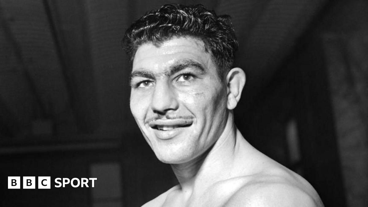 Boxer Jack Gardner punching Johnny Williams in the face, causing him to lean back on to the ropes of the boxing ring.