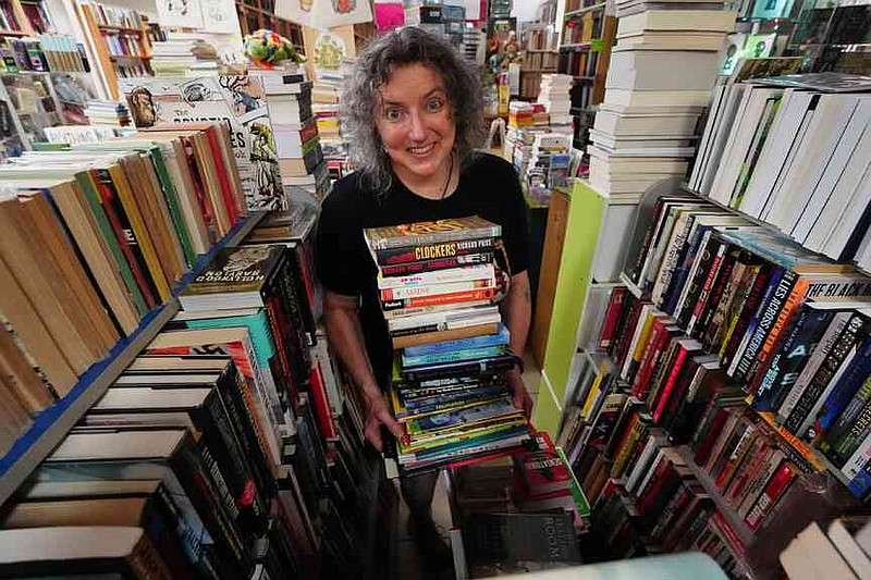 Michelle Souliere, owner of the Green Hand Bookstore, carries a stack of books to the shelves, in Portland, Maine, on Thursday, Aug. 7, 2025. (AP Photo/Robert F. Bukaty)