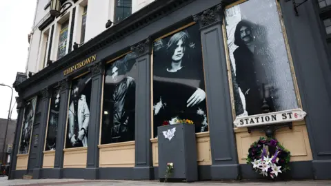 EPA Black and white images of four young men adorn the outside of a pub. All of them have long hair, three have big moustaches.
