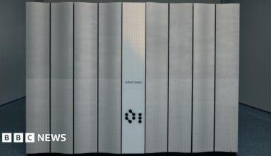 A front view of the new quantum computer Quartet. It has Oxford Ionics written in front. One of its buttons is light up in green.