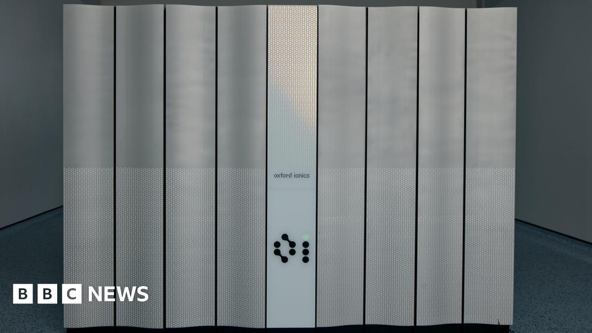 A front view of the new quantum computer Quartet. It has Oxford Ionics written in front. One of its buttons is light up in green.