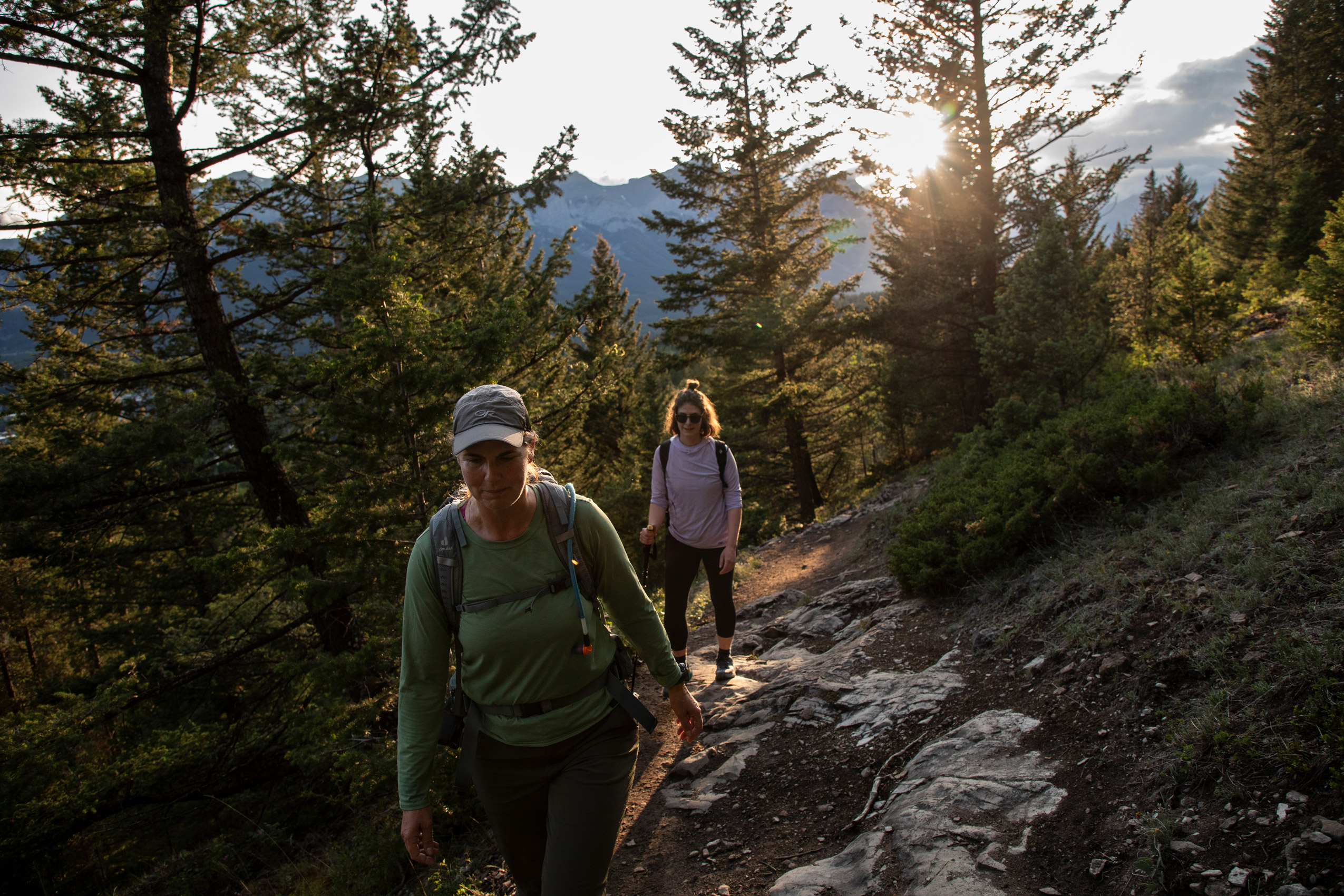 Two hikers on a Rocky Mountain trail as the sun dips toward the horizon