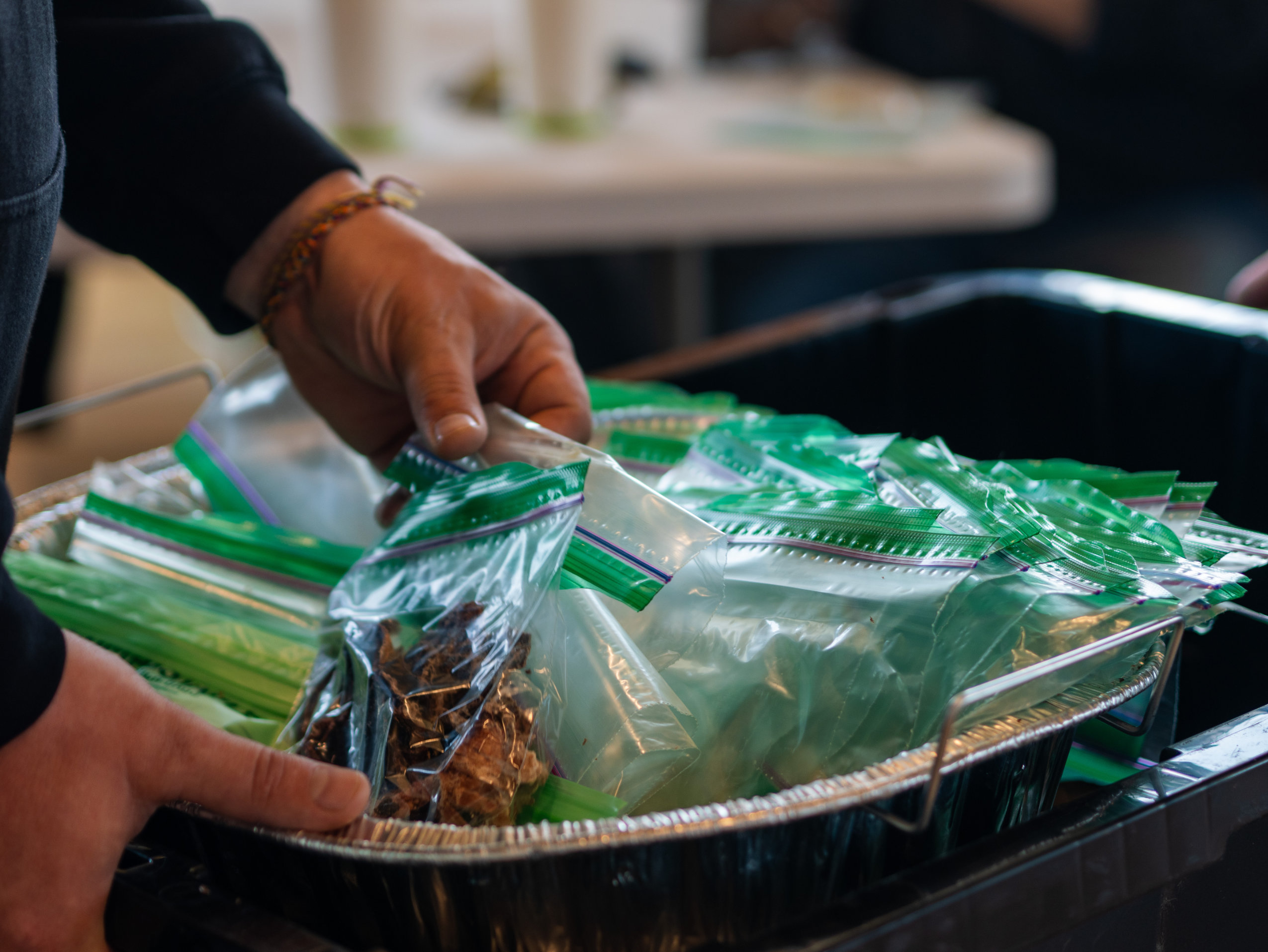 A hand reaches into a basket containing plastic baggies full of dried caribou meat during the Caribou Days festivities in Old Crow, Yukon.