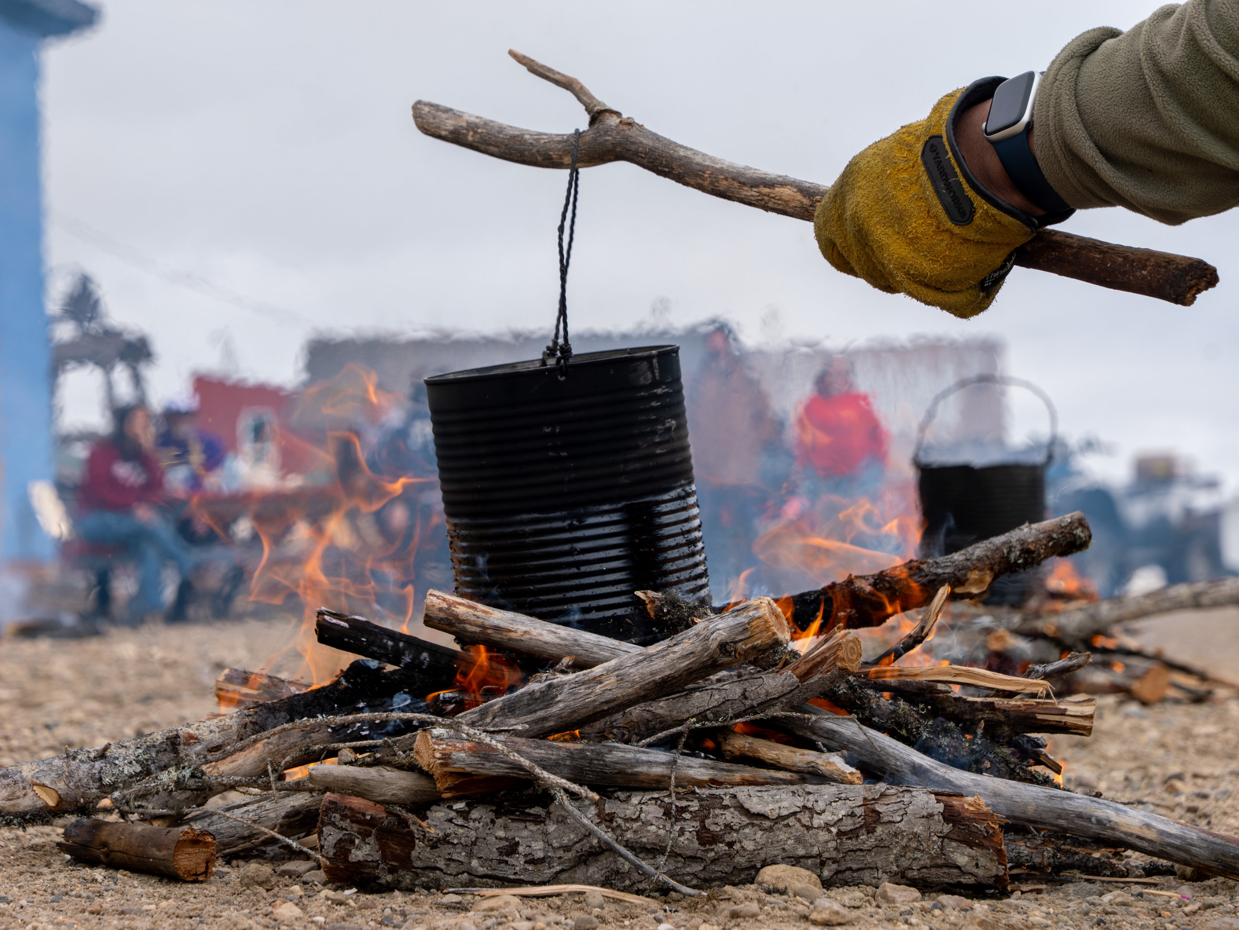 A close-up image of a blackened can suspended above a bonfire.