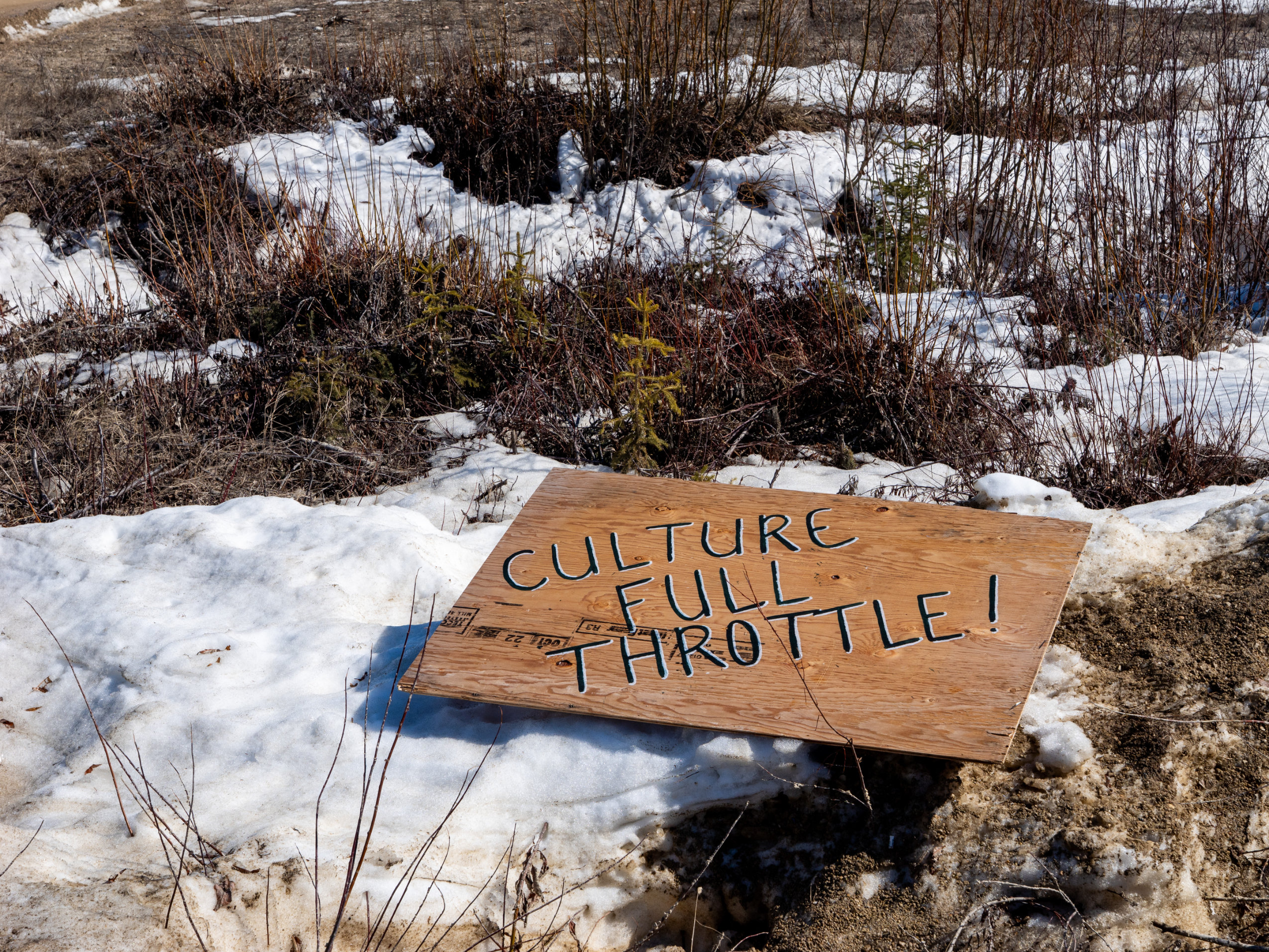 A sign that reads "CULTURE FULL THROTTLE!" lies on the ground.