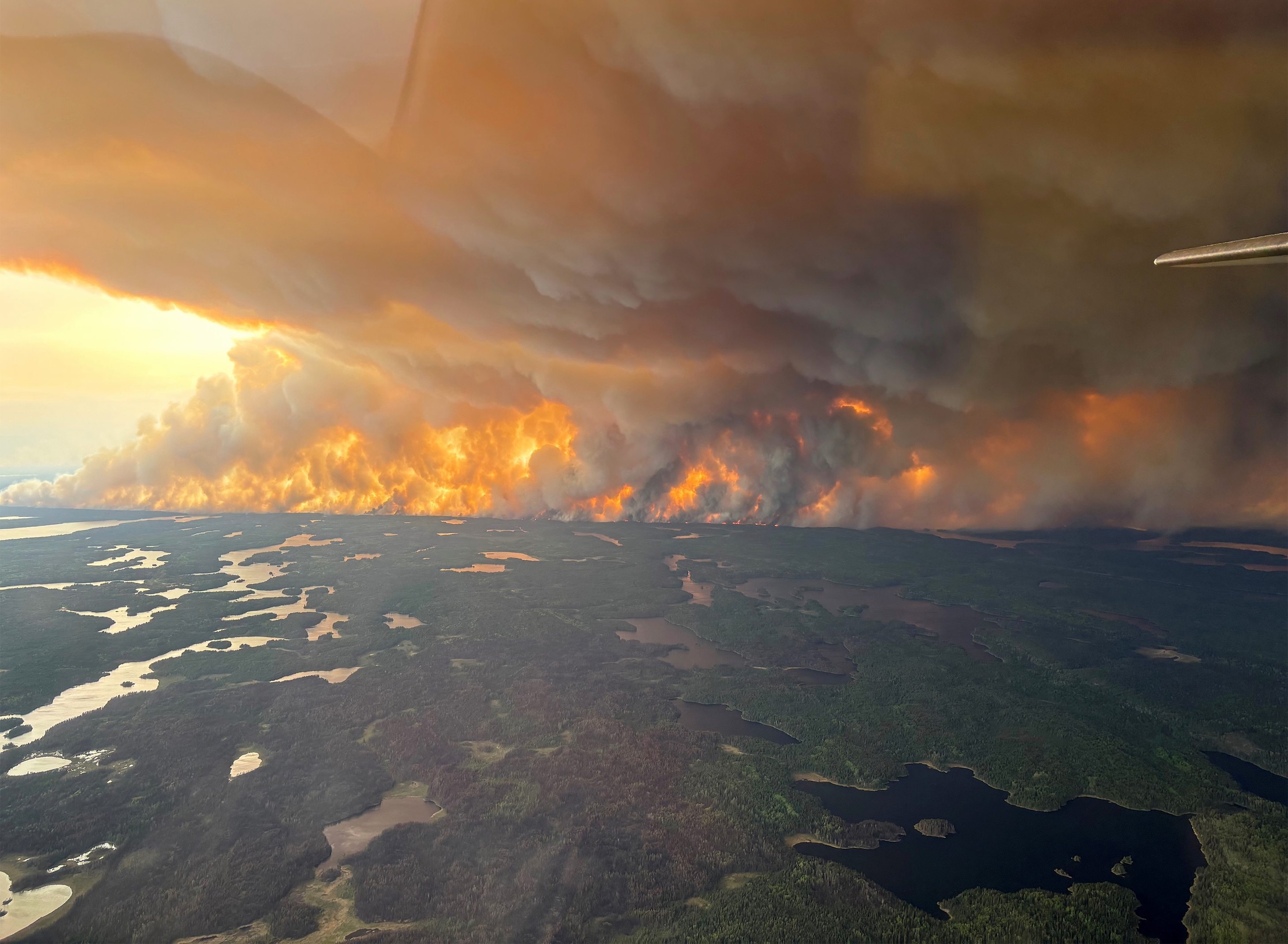 Aerial view of orange flames and large plumes of smoke rising from the forests near Flin Flon in northern Manitoba