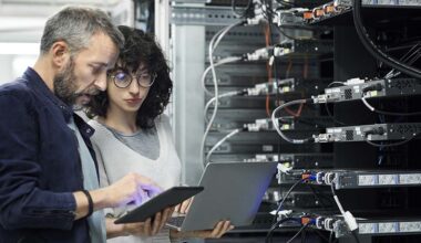 Male technician showing digital tablet to female coworker. Engineer working with colleague at workplace. They are in server room.