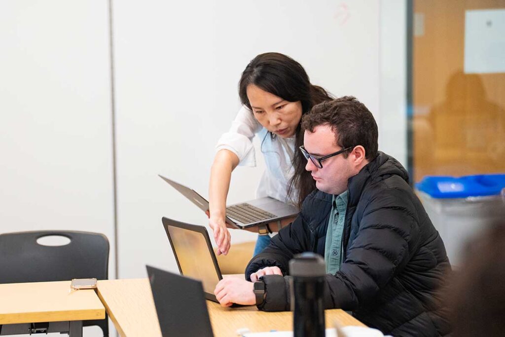 In the Computers and Society course, Jia Tao, associate professor of computer science (left), guides students as they explore the potential benefits, limitations, and dangers of technology