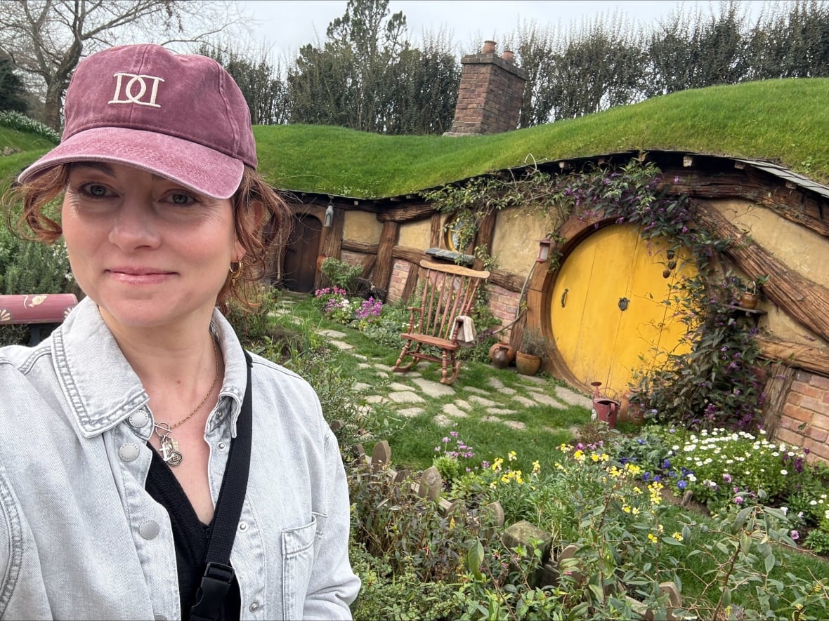 A woman takes a selfie with a movie set from The Hobbit and Lord of the Rings in the background.