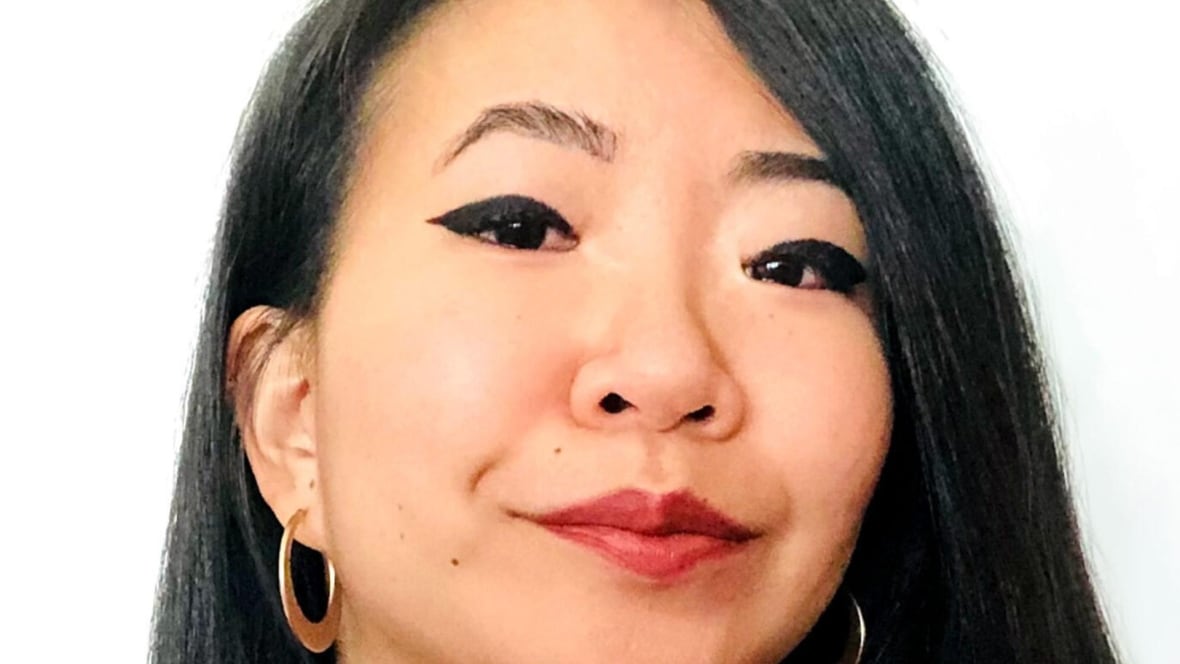 A woman with long black hair is smiling at the camera. 