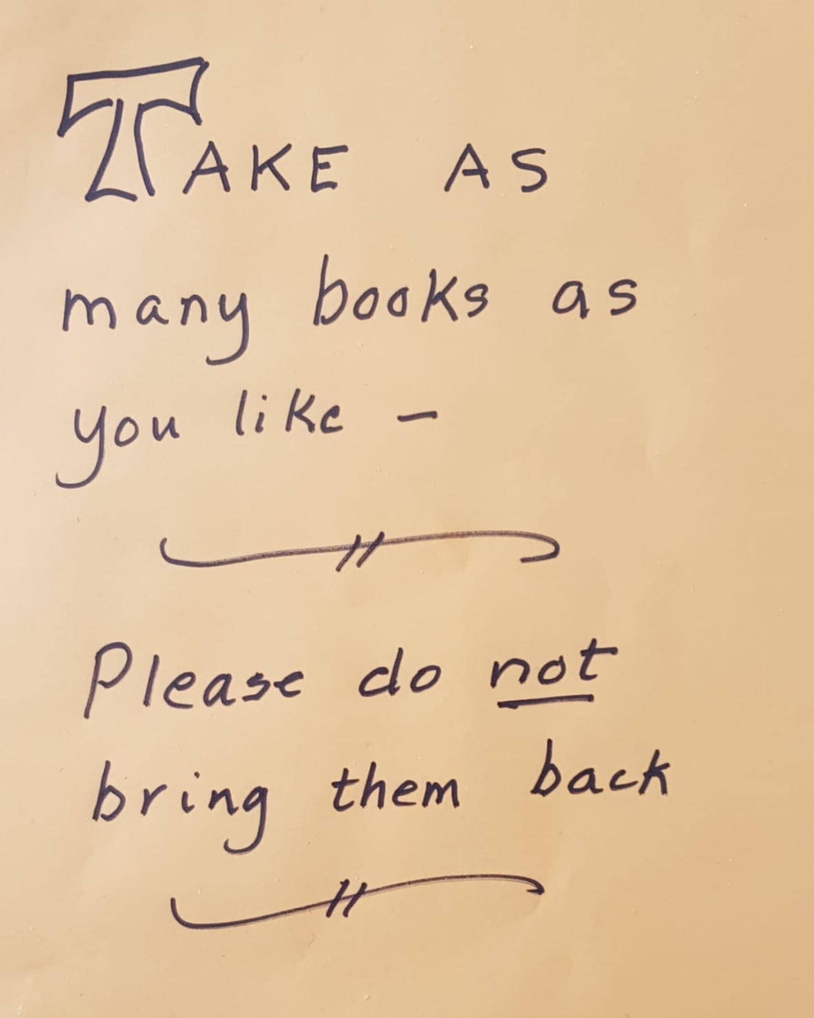A hand written sign saying "Take as many books as you like. Please do not bring them back."