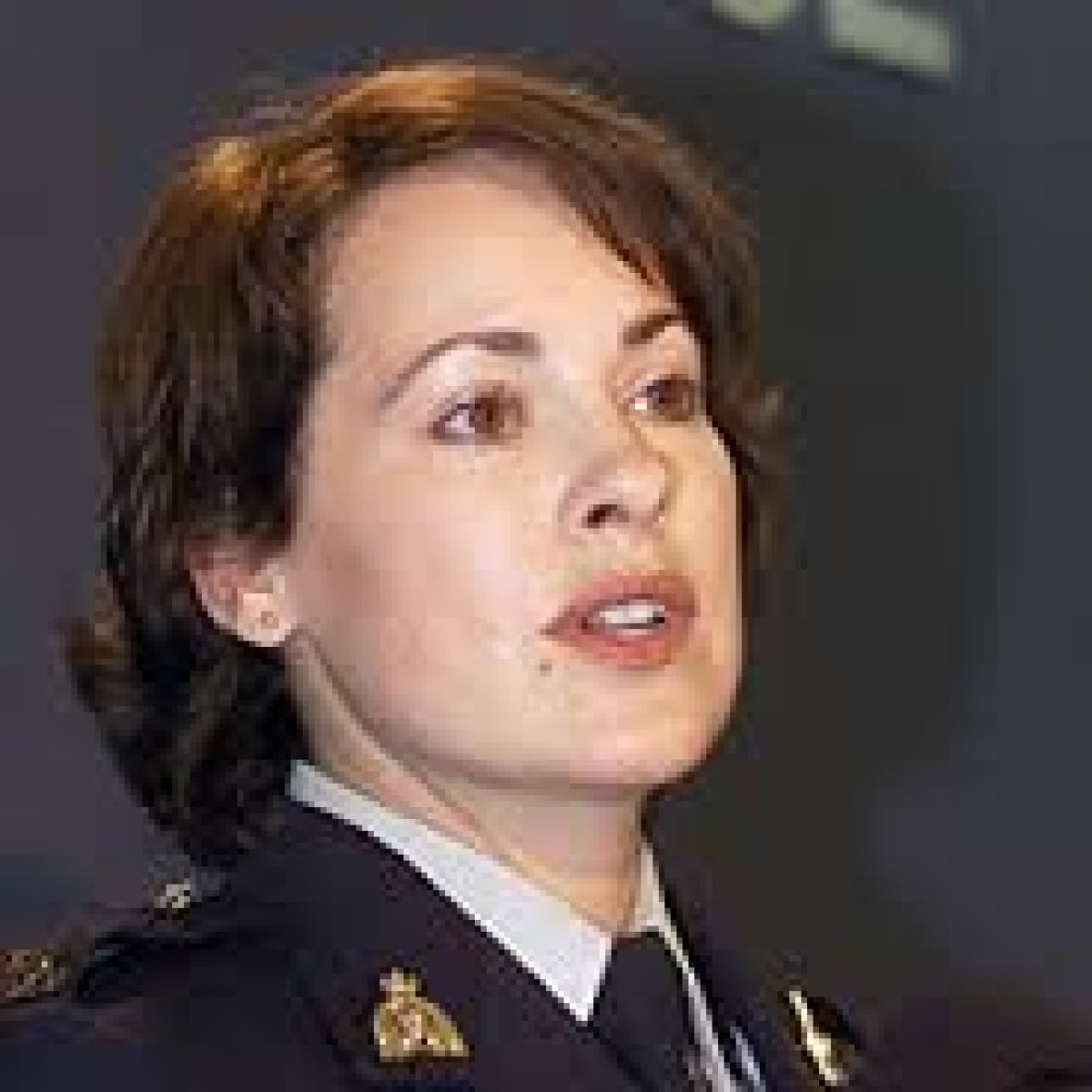 An RCMP officer speaks in front of a banner.