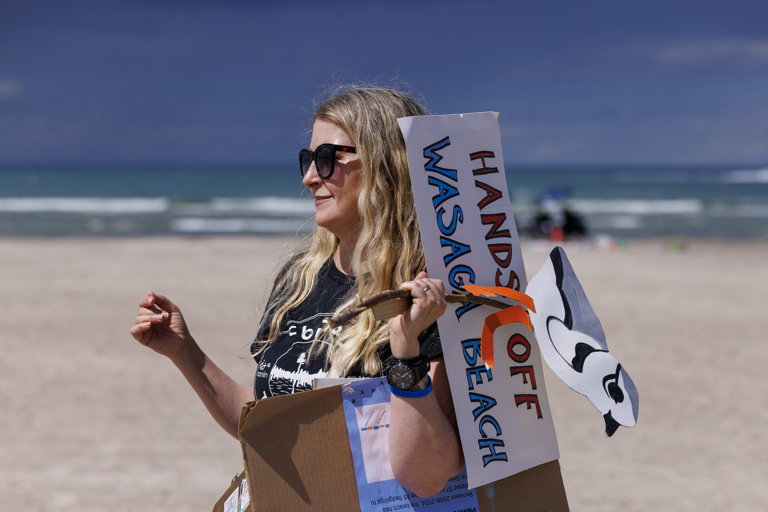 On Wasaga Beach, a protester holds a sign reading "Hands off Wasaga Beach."