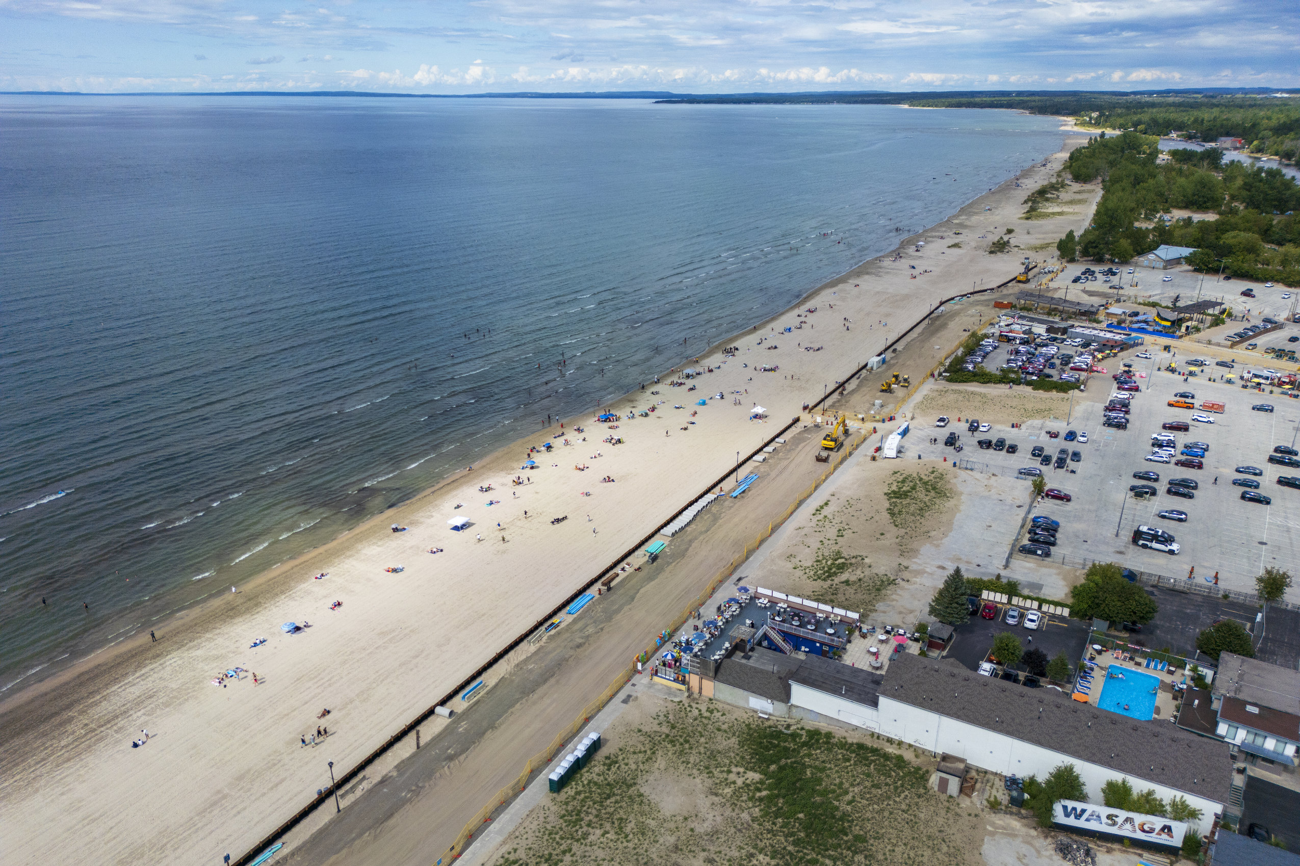 An aerial view of Wasaga Beach. On the left, Lake Huron and the sandy shoreline. On the right, a parking lot.