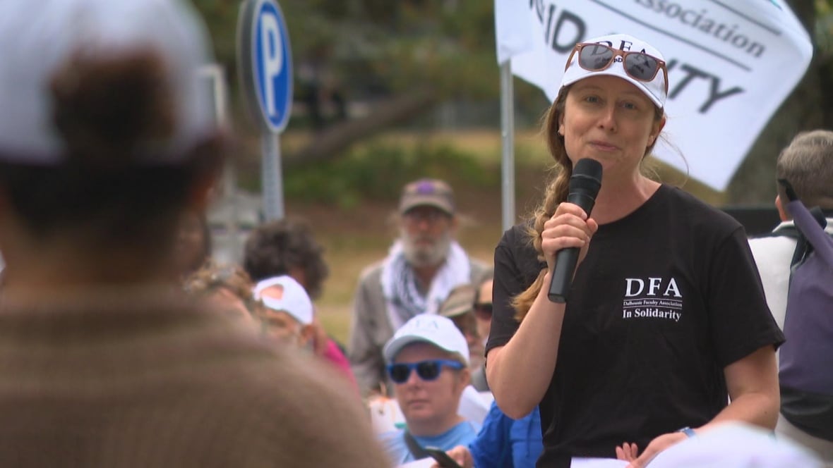 A woman looks into camera, in the background people. 