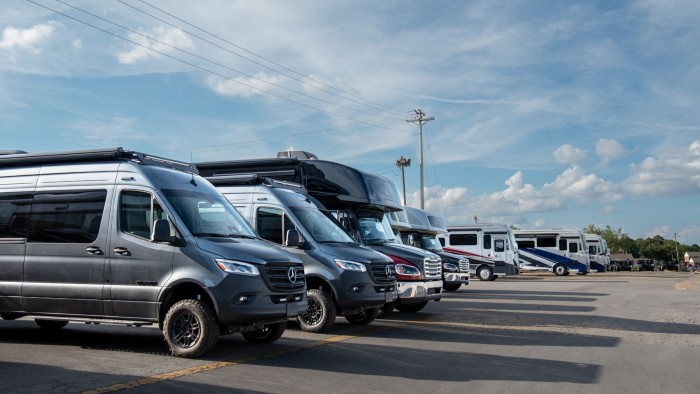 Several new Tiffin Motorhomes vehicles lined up for sale on a lot under a partly cloudy sky