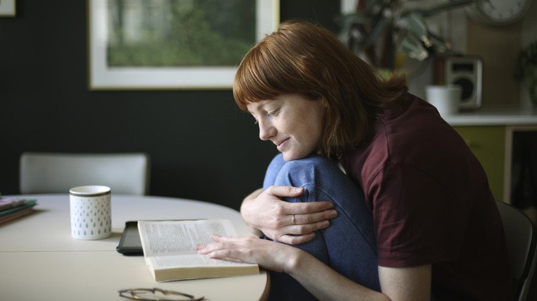 A woman sits at a table to read a book