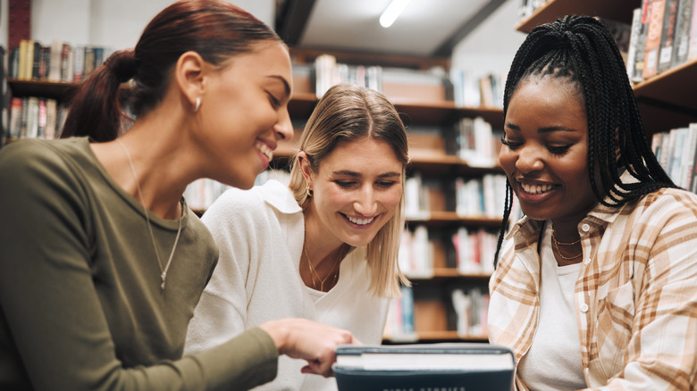 A group of friends in a bookstore looking at a book