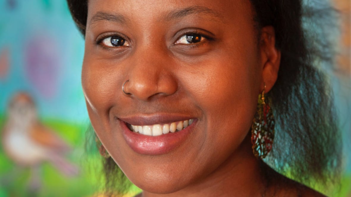 A headshot of a woman in a bun with circle earrings smiling at the camera.