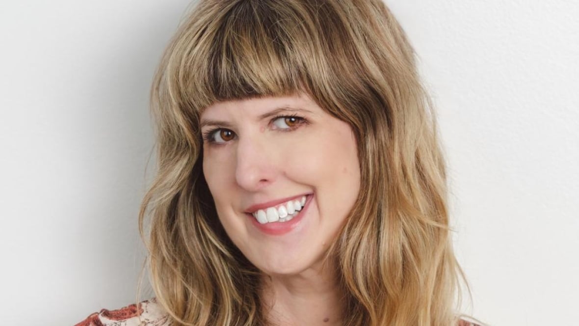 A blonde white woman smiles at the camera. 