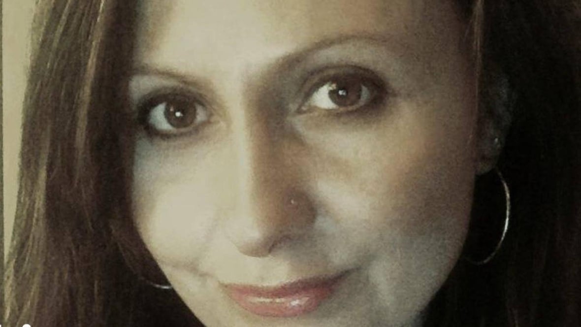 An author headshot photo of a woman wearing hoop earrings is smiling at the camera. 