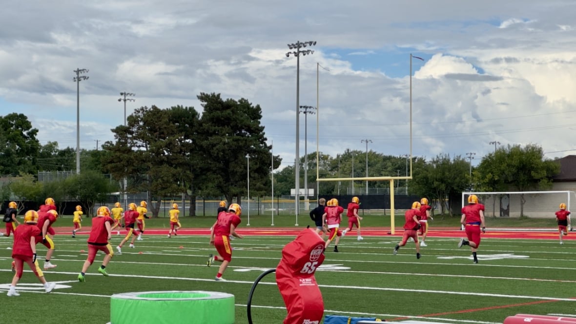 Football players run across a field, doing a drill.