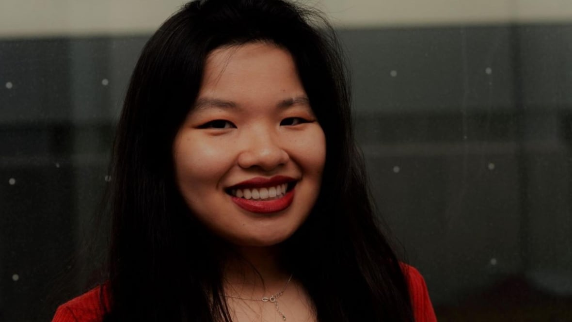 A woman with long black hair is smiling at the camera. 