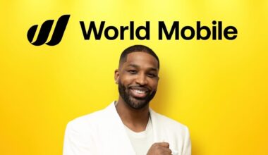 A man in a white jacket smiles against a yellow background with "World Mobile" text above.