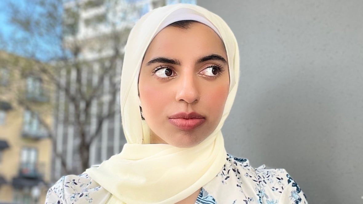 A woman wearing a white hijab is smiling at the camera. 