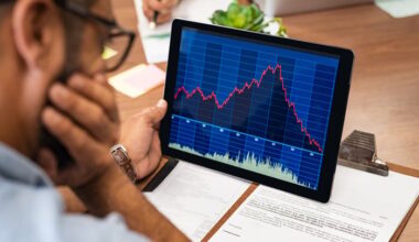 A visibly worried person looking at a rapidly rising then plunging stock chart displayed on a tablet.